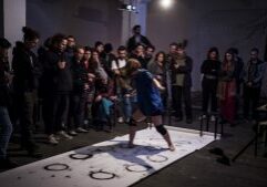 Several people crowded around a performance on a white sheet